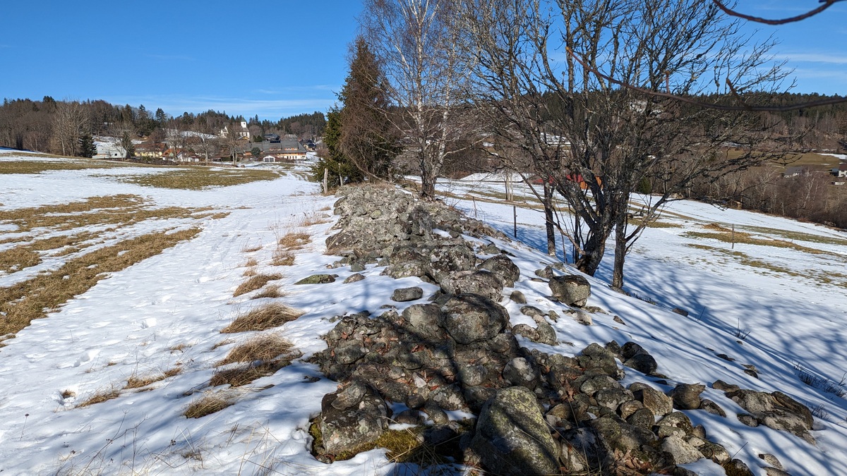 Steinwall im Schnee nahe einer offenen Fläche